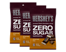 Three bags of Hershey's Zero Sugar caramel-filled chocolate candy are displayed, featuring bold text highlighting "ZERO SUGAR" and "ASPARTAME FREE," with each bag containing 3 ounces.