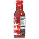 A clear glass bottle of zero-sugar tomato ketchup features a red cap and label with the product name and nutrition facts, alongside illustrations of ripe tomatoes.