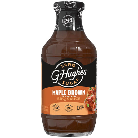 A clear bottle of G. Hughes Maple Brown flavored BBQ sauce, labeled as zero sugar, featuring a black and orange design with nutritional information, sits against a plain background.