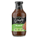 A clear bottle of G. Hughes Zero Sugar Mesquite Flavored BBQ Sauce displays its label with nutritional information, emphasizing it's gluten and dairy-free, suitable for low-calorie diets.