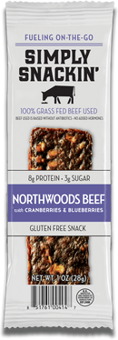 A packaged snack bar labeled "Simply Snackin' Northwoods Beef with Cranberries & Blueberries," highlighting its 100% grass-fed beef, gluten-free status, and nutritional information.