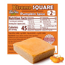 A square dessert bar with a pumpkin spice topping sits in front of an orange packaging that displays nutritional information and a guarantee, with small pumpkins in the corner for seasonal context.