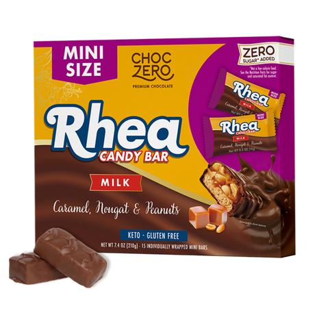 A box of Rhea candy bars features a colorful design with the text "Mini Size" and "Milk," showcasing the candy's caramel, nougat, and peanuts, with two bars in front.