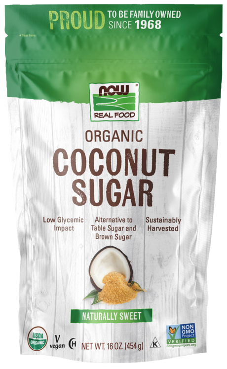 A green and white bag of NOW Real Food Organic Coconut Sugar features a coconut graphic, highlights its low glycemic impact, and states it is sustainably harvested and vegan.
