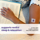 A person rests their hand on an open book while wearing a patch on their arm that promotes restful sleep and relaxation, with text highlighting its 8-hour wear and easy application.