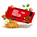 A package of high protein pasta with a red label features tagliatelle noodles, surrounded by fresh basil leaves and tomato slices, emphasizing its keto-friendly attributes.