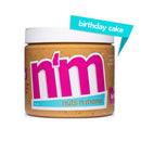 A jar of "n'm" nut butter with a birthday cake flavor label, featuring bright pink and blue text, sits against a white background, highlighting its unique flavor and protein content.