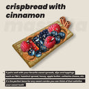 A slice of crispbread topped with cinnamon, peanut butter, and an assortment of fresh berries, presented on a neutral background with text highlighting its versatility as a sweet snack base.