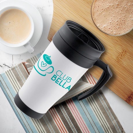 A white travel mug with a black lid and the text "CLUB BELLA" is placed on a striped cloth, alongside a cup of coffee and a wooden cutting board.